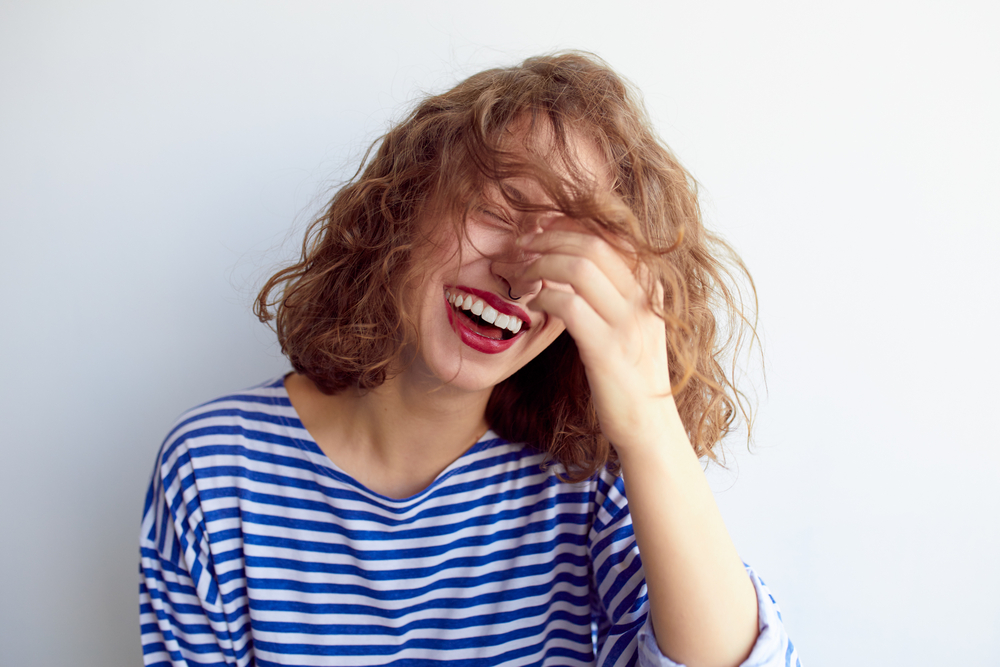 Laughing woman in marine shirt with curly hair over white wall(Mark Nazh)S