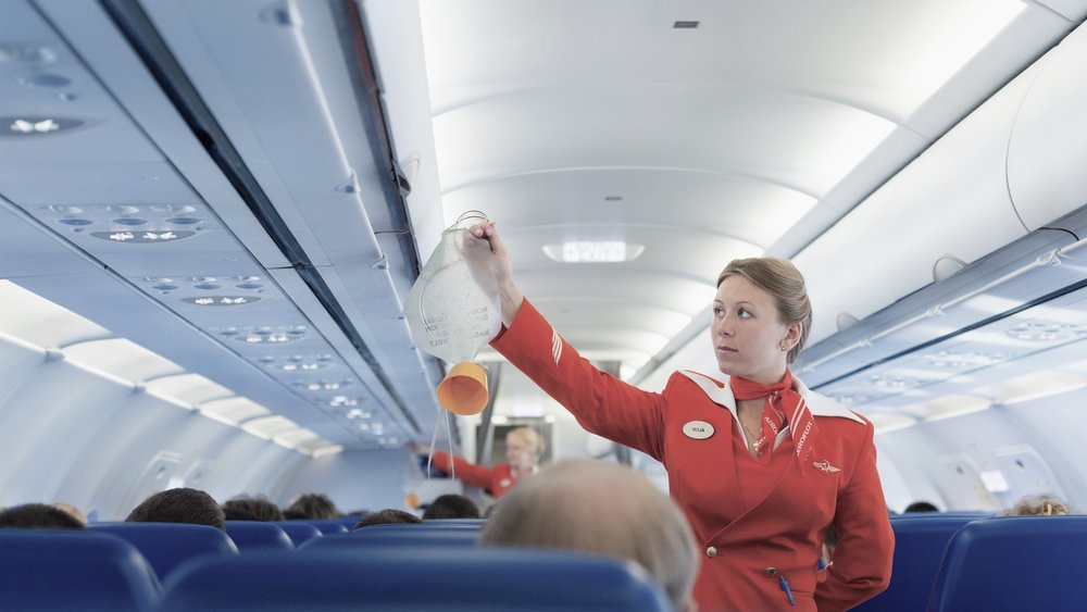 air hostess demonstrating the use of an oxygen mask