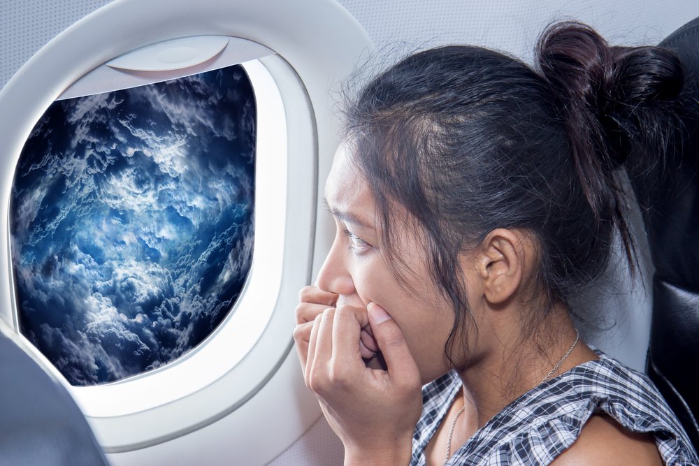 Scared woman looks at the clouds from an air plane window Traveler looking out the airplane window on a raging storm. Passenger has a fear of plane crash. Woman on the aircraft looking at storm clouds.