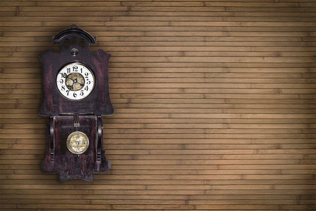 Old pendulum clock on the background of wooden wall