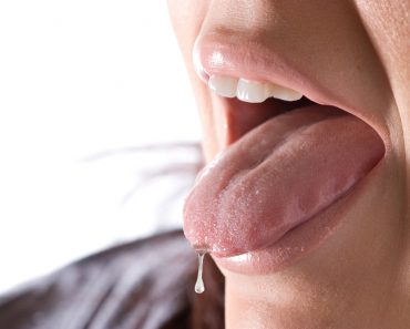 Closeup of a young woman sticking out her tongue saliva