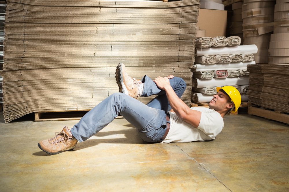 Side view of male worker lying on the floor in warehouse man hurt ouch.jpg