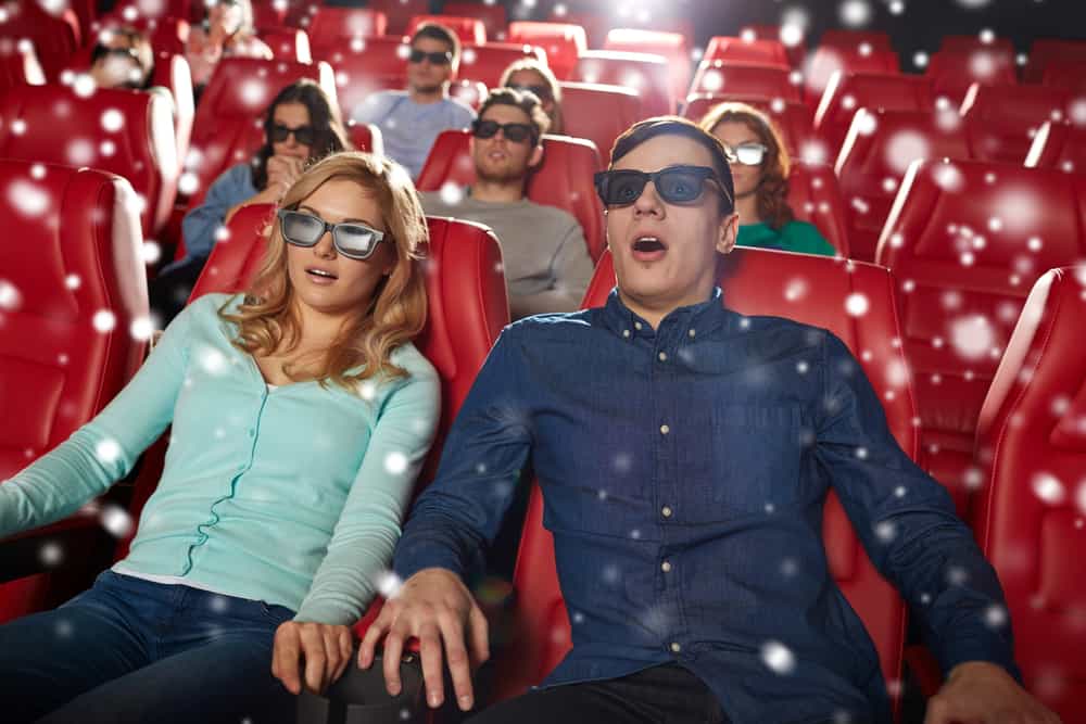 cinema, technology, entertainment and people concept - scared friends or couple with 3d glasses watching horror or thriller movie in theater with snowflakes Watching a scary movie