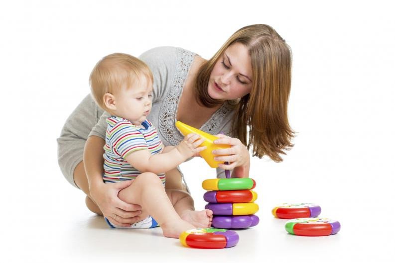 baby boy and mother playing together with construction set toy handing toy to mother