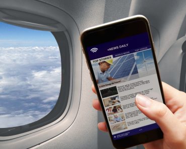 Mobile in girl hand reading news connected to the airplane wifi window cloud flying