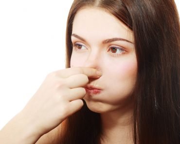 Young Woman Holding her Nose smelling something stinking popping ear