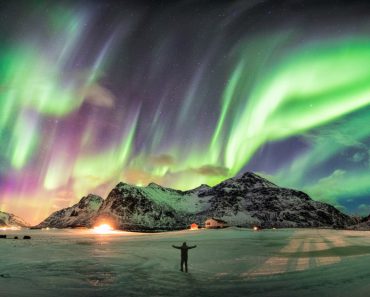 Aurora borealis (Northern lights) over mountain with one person at Skagsanden beach, Lofoten islands, Norway - Image(Mumemories)S