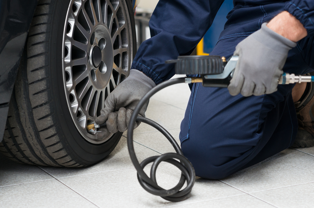 Closeup Of Mechanic At Repair Service Station Checking Tyre Pressure With Gauge - Image(Rido)s