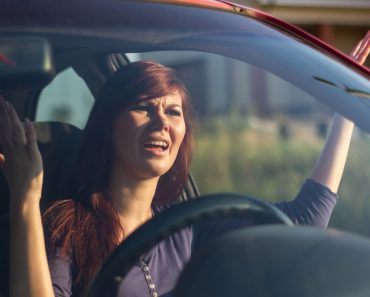 Closeup portrait, angry young sitting woman pissed off by drivers in front of her and gesturing with hands. Road rage traffic jam concept - Image(perfectlab)s