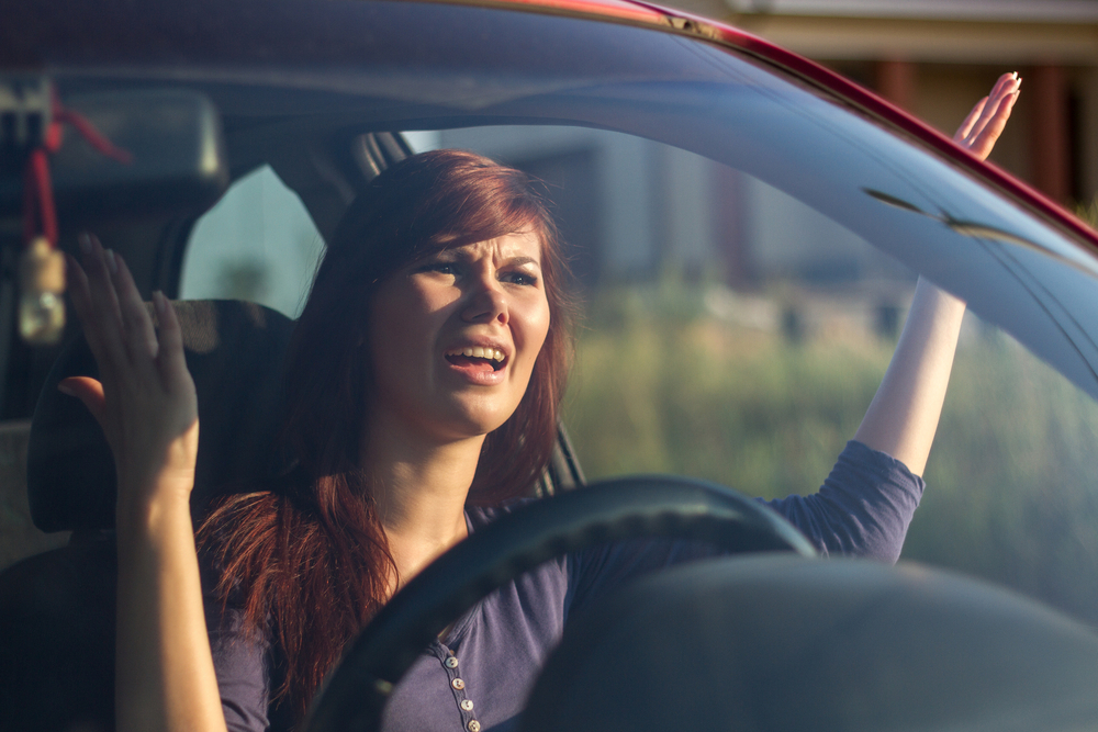 Closeup portrait, angry young sitting woman pissed off by drivers in front of her and gesturing with hands. Road rage traffic jam concept - Image(perfectlab)s