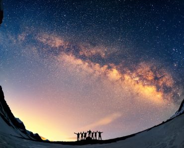 Teamwork and support. A group of people are standing together holding hands against the Milky Way in the mountains. - Image( Anton Jankovoy)S
