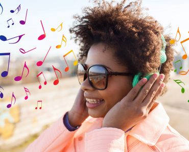 technology, lifestyle and people concept - smiling african american young woman or teenage girl in headphones listening to music outdoors over colorful musical notes background - Image( Syda Productions)s