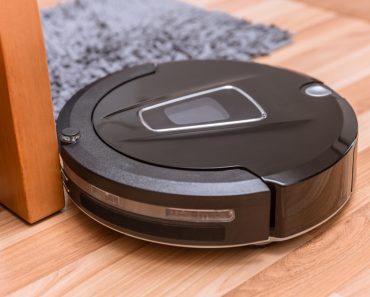 Robot vacuum cleaner on laminate wood floor with carpet cleaning - Image( Quality Stock Arts)S