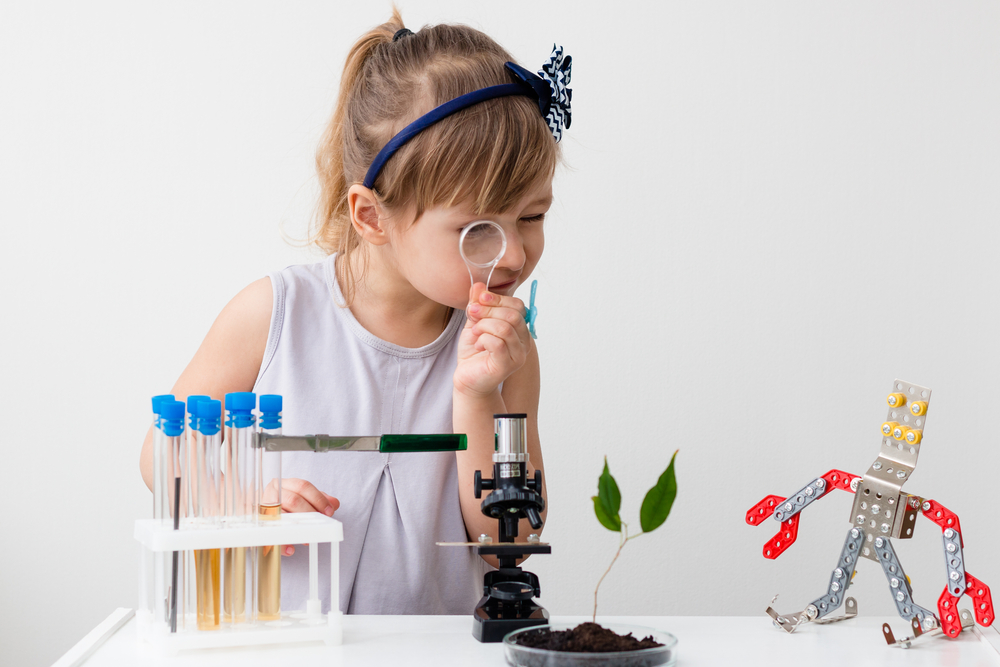 Little girl is behind the desk. Microscope and the tree are near her. Little robot. E-learning. Stem education. - Image(AlesiaKan)s