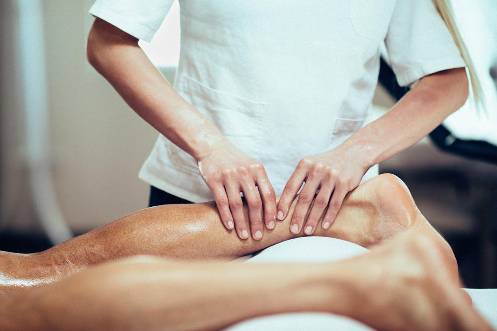Sports Massage. Massage therapist working with patient, massaging his calves. Toned image. - Image(Microgen)s