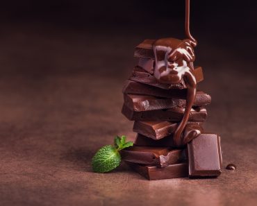 melted chocolate pouring into a piece of chocolate bars with green mint leaf on a table - Image( Dima Sobko)s
