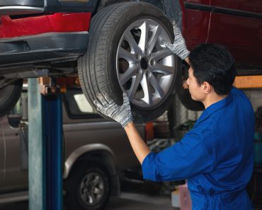 Asian mechanic checking wheel under the car to repair(ReeAod)s