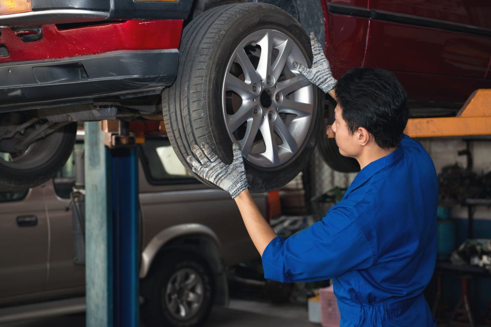 Asian mechanic checking wheel under the car to repair(ReeAod)s