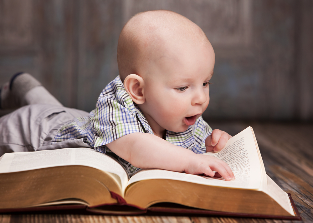 Reading. Adorable baby boy lying on the floor reading a giant book(Michelle D. Milliman)s