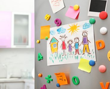 Sheets of paper, child's drawing and magnets on refrigerator door in kitchen( New Africa)s