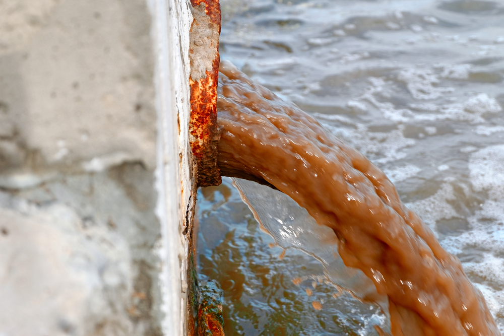 Side wiew of dirty water discharging from rusty pipe into the river(Mettus)S