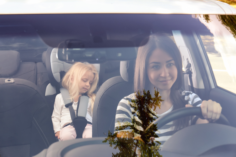 Young woman driving car with small girl in safety seat( Africa Studio)S