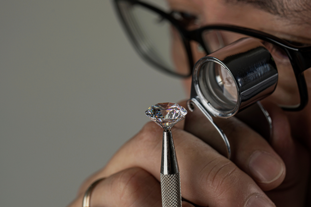 Man jeweller examines polished diamond through magnifier(EgolenaHK)s