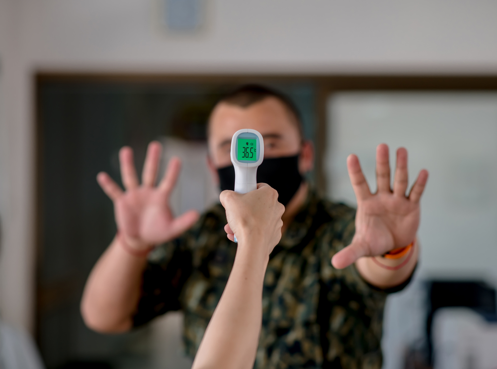 Close-up of a protective masked man ready to be used with an infrared forehead thermometer(JETACOM AUTOFOCUS)s