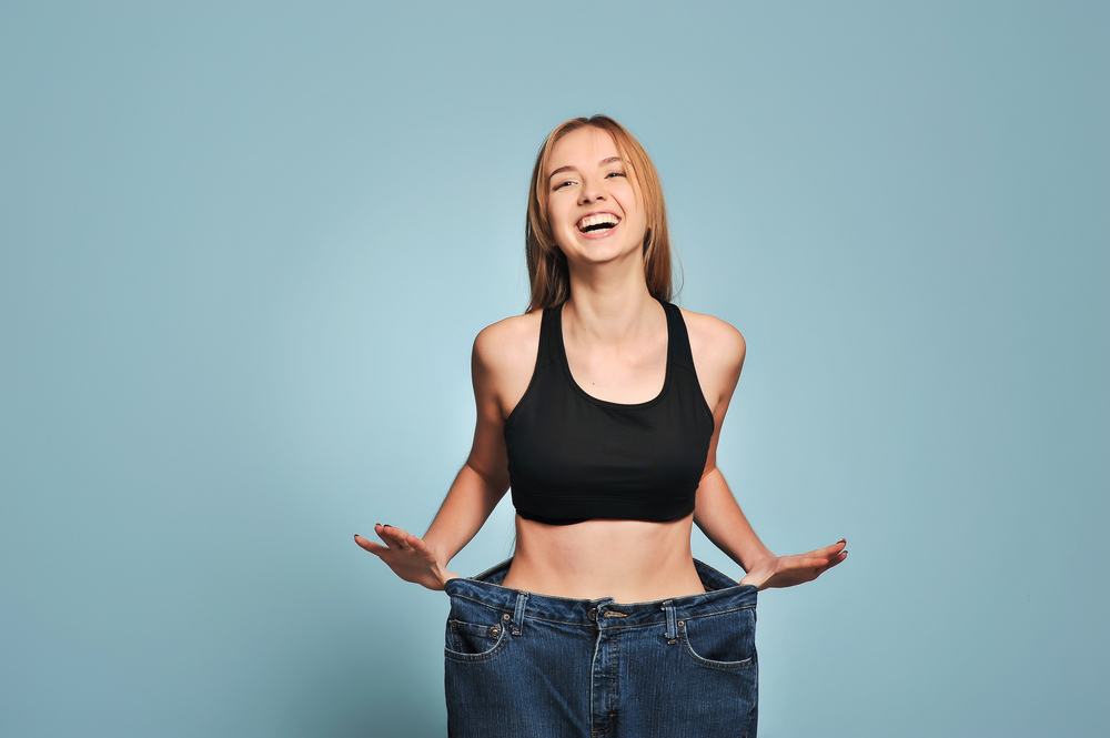 Women shows her weight loss. Isolated on blue background(Ruslan_127)S
