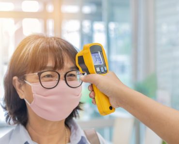 Security guard using digital medical electronic thermometer measures checking body temperature screening passengers(Soonthorn Wongsaita)s
