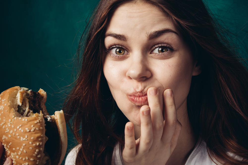 Woman eating a hamburger, chewing a hamburger, hamburger in hand(ViChizh)s