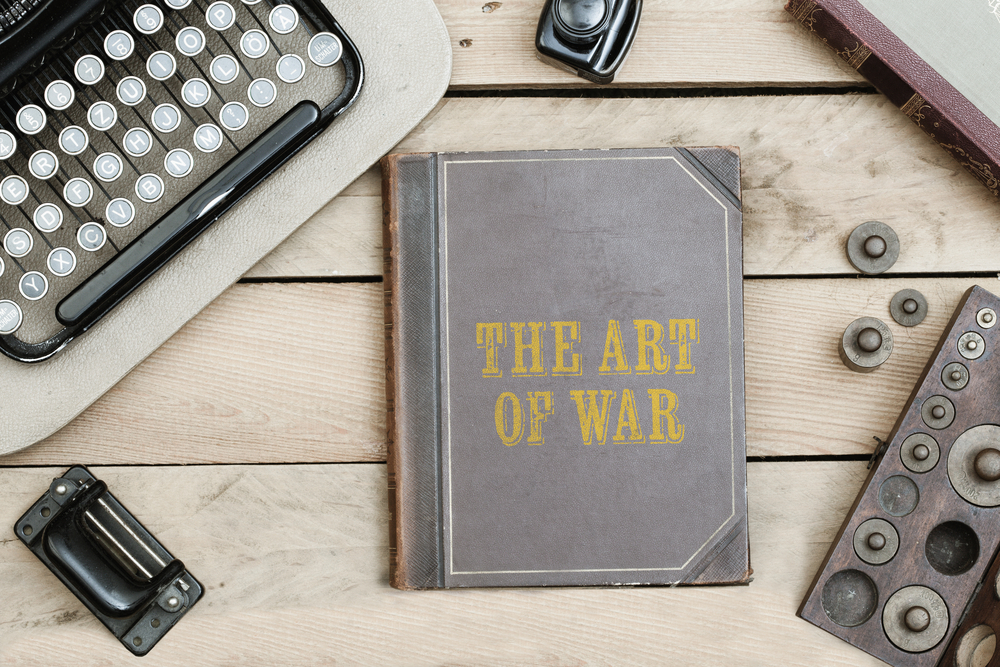 The Art of War text on cover of old book on office desk with vintage type writer machine(MichaelJayBerlin)S
