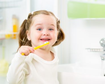 smiling kid girl brushing teeth in bathroom(Oksana Kuzmina)s