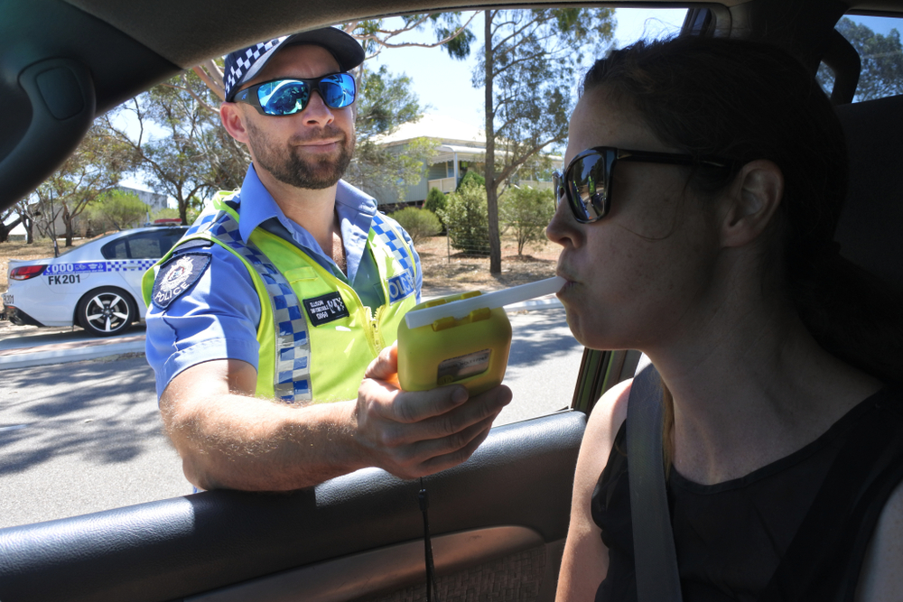Australian traffic police officer using breathalyzer on woman driver during field sobriety testing(ChameleonsEye)s
