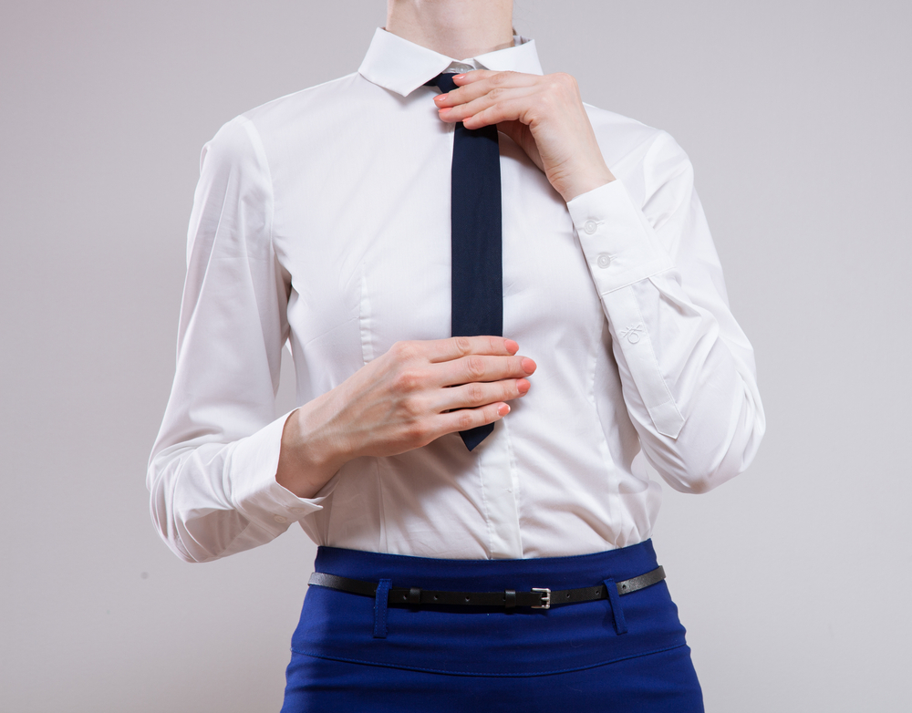 Unrecognizable businesswoman sets the necktie on neutral background(Maryna Pleshkun)S