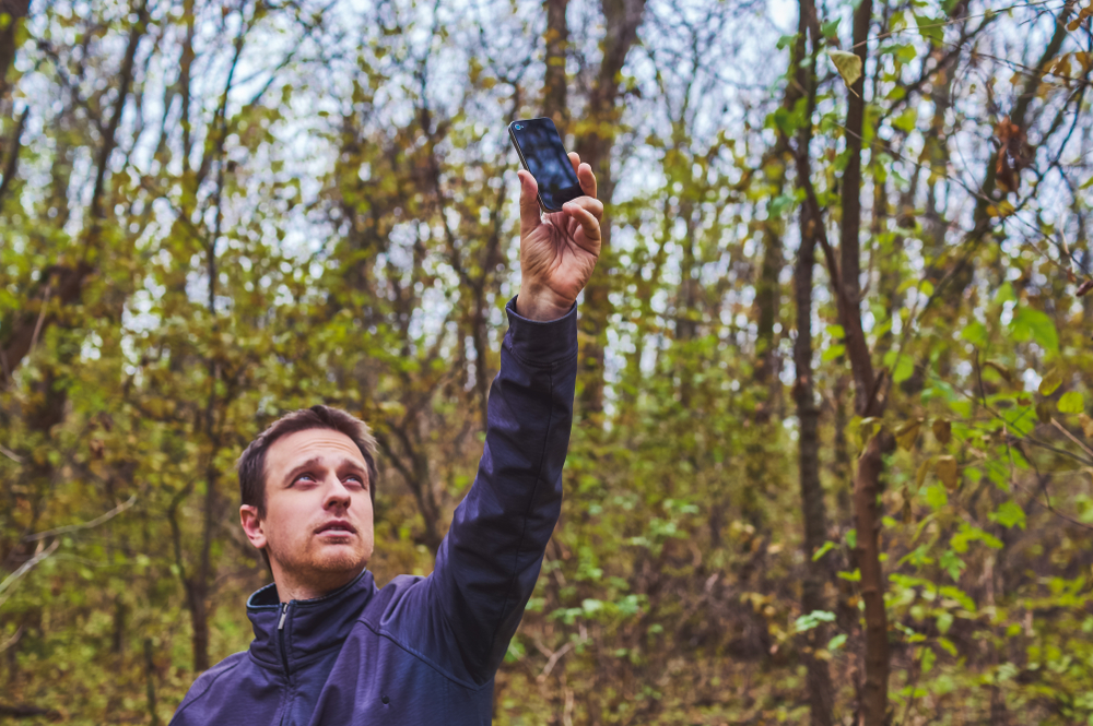 Man with his mobile smart phone searching for reception signal in the forest(Alrandir)s