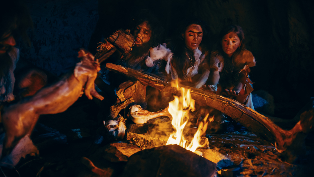 Neanderthal or Homo Sapiens Family Cooking Animal Meat over Bonfire and then Eating it(Gorodenkoff)S