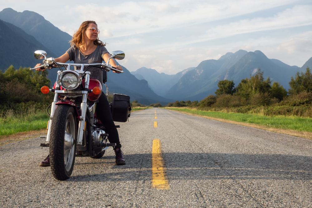 Woman,Riding,A,Motorcycle,On,A,Scenic,Road,Surrounded,By