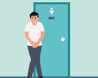 Stressed man standing standing at the closed toilet door
